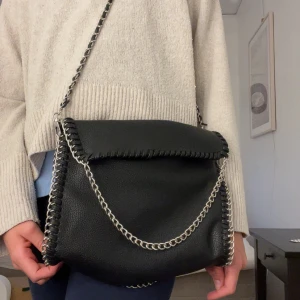 Stella McCartney  - Säljer en otroligt fin väska !SOM LIKNAR STELLA MCCARTNEY! (Aldrig använd!) Den ger en skön look med texturen och de silvriga kedjorn. Väskan går att styla på många sätt så som på bilderna.  Väska är i nyskick, har aldrig använts där av priset, men lapparna är borta. 