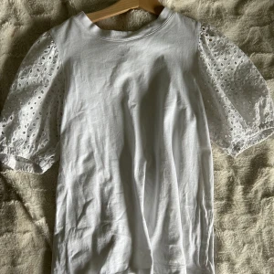 Vit topp med puffärmar och broderade detaljer - Säljer en vit topp i bra skick med korta puffärmar i broderad spets. Säljer eftersom att den är för liten💕