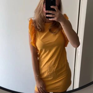Orange klänning  - Säljer en kort orange klänning från Gina Tricot med volangdetaljer på axlarna. Klänningen är i storlek S och är helt oanvänd. Säljer pga den inte passar min stil. (Färgen är lite mer orange än vad den ser ut på bilderna)🤗💕