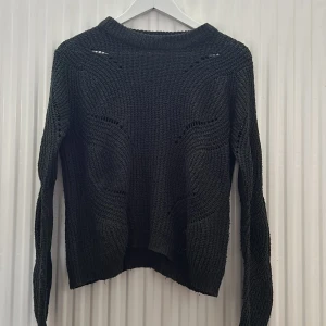 Mörkgrå stickad tröja från Jacqueline de Yong - Säljer en mörkgrå stickad tröja från Jacqueline de Yong i storlek XS. Tröjan har ett snyggt hålmönster och ribbad krage, ärmar och nederkant. Perfekt för lager på lager under kyliga dagar.