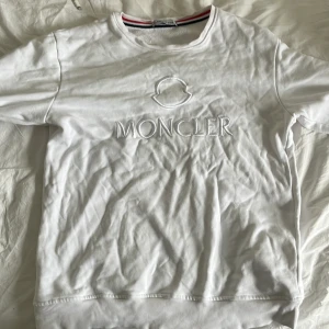 Vit Moncler sweatshirt med broderad logga - Säljer en vit sweatshirt från Moncler med broderad logga och emblem på bröstet. Tröjan har rund halsringning och ribbade muddar vid ärmslut och nederkant. Enkel och stilren design som passar till mycket.