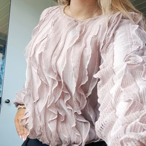 Ljusrosa volangblus från Kappahl - Säljer en ljusrosa blus från Kappahl med volangdetaljer framtill och på ärmarna. Sparsamt använd och är i storlek S. Helt slutsåld på hemsidan!💕🩷