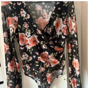 Blommig body - En jätte fin blommig body som går omlott över brösten och har väldigt puffiga armar! Sparsamt använd💕