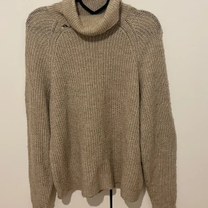 Beige stickad polotröja från ONLY - Mysig beige stickad polotröja från ONLY. Tröjan har lång ärm, grovstickad struktur och hög polokrage. Perfekt för kyliga dagar och enkel att matcha med olika outfits.