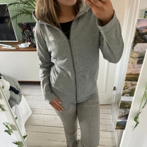 Grå hoodie från Nike - Säljer en stilren grå hoodie från Nike med dragkedja och huva. Perfekt för en avslappnad look. Den har långa ärmar och en klassisk passform med fickor framtill. Enkelt att matcha med olika outfits. PRISET GÅR ATT PRUTA!