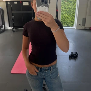 Brun ribbad topp med öppen rygg - Säljer en brun ribbad topp med korta ärmar och en snygg öppen rygg. Toppen är croppad och har en tight passform. 