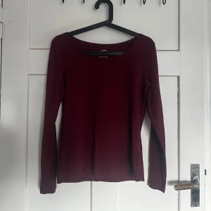 Vinröd långärmad topp från lager 157 - Snygg vinröd långärmad topp. Perfekt för höst och vinter med sin djupa färg och enkla design. Passar bra till både jeans och kjol. Ett måste i garderoben för en stilren look.