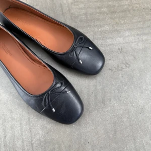 Svarta ballerinaskor  - Snygga svarta ballerinaskor med en liten rosett på ovansidan. Perfekta för en stilren look och bekväma att bära hela dagen.