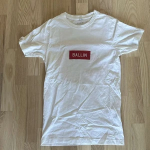 Vit t-shirt med rött tryck från Ballin - Säljer en vit t-shirt från Ballin med ett rött tryck på framsidan och ett stort nummer 23 i rött och svart på baksidan. Perfekt för en sportig look!