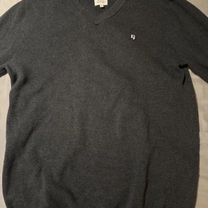 Mörkgrön tröja med v-ringning - Säljer en stilren grå tröja från Garcia med v-ringning. Perfekt för en avslappnad men ändå snygg look. Tröjan har en liten broderad logga på bröstet. Nypris 600.