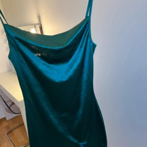 Grön axelbandslös klänning från Shein - Snygg grön axelbandslös klänning från Shein i ett glansigt material. Perfekt för en kväll ute eller en speciell tillställning. Klänningen har en elegant och enkel design som framhäver en stilren look.