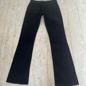 Svarta lågmidjade bootcut jeans - Superfina jeans från Wrangler, midjemått 39 cm och innerbenslängd 91 cm