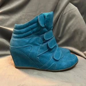 Isabel Marant liknande skor - Snygga turkosa boots med kilklack och flera kardborreband för en unik look. Perfekta för att ge en färgklick till din outfit. De har en modern design med en bekväm passform. Skicket beskriver bilderna