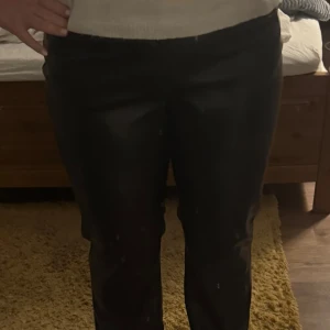 Svarta skinnbyxor - Snygga svarta skinnbyxor med en tight passform. Perfekta för en stilren look. Byxorna har en hög midja och en rak siluett som ger en modern känsla.