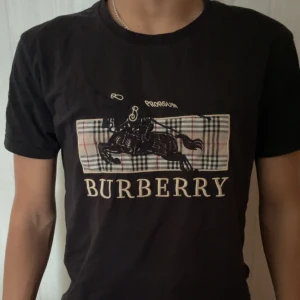Svart t-shirt från Burberry - Riktig snygg burberry T-shirt i perfekt skick med ett litet broderat emblem på armen. Säljer denna för den inte kommer till använda. Vid minsta lilla fundering skriv! (Priset kan diskuteras) (prislappen finns)