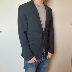 Grå Dondup kavaj 🙌nyskick🙌 - Riktigt fet grå kavaj från Dondup. Kavajen är i storlek 46 vilket motsvarar S. Nypris är 🙌4000-5000kr🙌 Kavajen är gjord av lana wool vilket är ett väldigt fint bomullstyg. Kavajen är relativt tunn så den är perfekt till sommaren. Tveka inte på att höra av er vid frågor och funderingar.