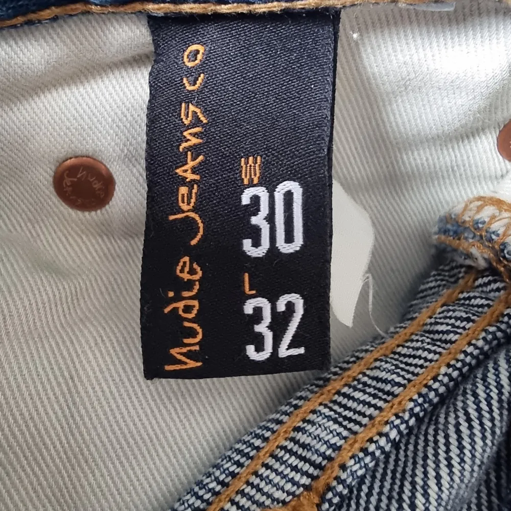 Säljer ett par klassiska blå jeans från Nudie Jeans. De har en snygg broderad detalj på bakfickan och en läderpatch med logotypen på baksidan. . Farkut & Housut.
