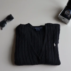  Ralph Lauren cardigan  - svart stickad tröja från Ralph Lauren med klassiskt kabelstickat mönster. Tröjan har en v-ringad hals och långa ärmar, Den ikoniska loggan är broderad på bröstet. Original priset som jag köpte den var 2 689 kr men säljer mycket billigare. 