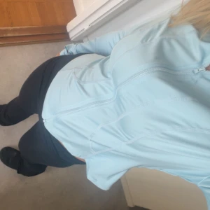 Ljusblå vindjacka med dragkedja - Säljer en ljusblå vindjacka med dragkedja. Jackan har en smidig och sportig design, perfekt för utomhusaktiviteter. Den är långärmad och har en figurnära passform.