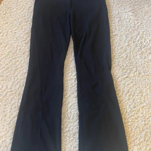 Svarta kostymbyxor från Nelly - Snygga svarta byxor från Nelly med en elegant bootcut-stil. Perfekta för en stilren look. Byxorna har en klassisk design som passar till många olika tillfällen. Aldrig använda! 