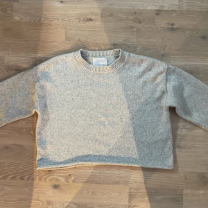 Beige stickad tröja från Zara - Säljer en mysig ljusgrå stickad tröja från Zara. Tröjan har en rund halsringning och långa ärmar, perfekt för kyligare dagar. Den är enkel och stilren, vilket gör den lätt att matcha med olika outfits. Säljer för att jag har växt ur den själv! 💞💞