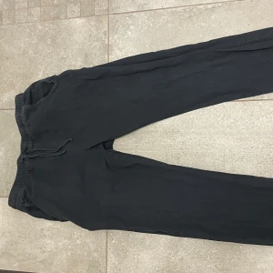 Svarta linnebyxor med snörning - Säljer ett par svarta mjukisbyxor med snörning i midjan. Från lager 157Byxorna har en avslappnad passform och är perfekta för en bekväm stil. De har elastiska muddar vid bensluten för en skön känsla.