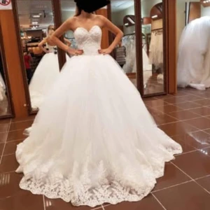 Vit axelbandslös brudklänning - Elegant vit brudklänning med axelbandslös design och vacker spetsdetalj. Klänningen har en lång, svepande kjol och en dramatisk släp. Perfekt för en sagolik bröllopsdag. Köpt för 30000. Säljes: högsta bud. Tidig hämtning prioriteras först. Kemtvättad. Storlek 34/36.