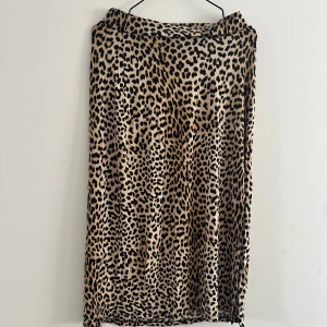 Leopardmönstrad långkjol Gina Tricot - Snygg långkjol från Gina Tricot med leopardmönster i beige och svart. Kjolen har en rak och flowy passform som ger en cool vibe. Perfekt för dig som vill sticka ut lite extra med ett djurmönster. Materialet känns mjukt och följsamt.