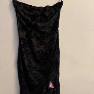 Svart blommig långklänning i sammet - Supersnygg svart långklänning med sammetsliknande blommigt mönster. 