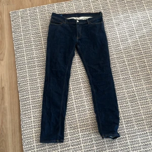 Mörkblå skinny jeans - Snygga mörkblå acne jeans med klassisk femficksdesign och orangea sömmar. Jeansen har normal midja och är tillverkade i stretchig denim för en tight passform. Perfekta för dig som gillar en stilren och enkel look.