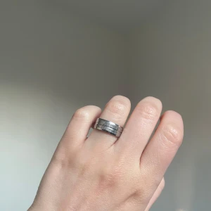Bred silverfärgad ring med glitter - Säljer en bred ring i silverfärg med två glittriga, strukturerade band som ger en cool och modern look. Ringen har en stilren design och passar perfekt för dig som gillar statement-smycken.