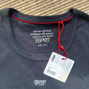 Svart t-shirt från Esprit XS - Svart t-shirt från Esprit i klassisk modell med rund hals och korta ärmar. T-shirten har en liten vit Esprit-logga på bröstet och är gjord i mjuk bomull.. Storlek XS. Aldrig använd.  Rändwrna på bilderna är endast solen genom fönstret. 