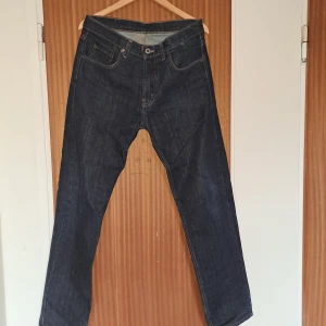 Mörkblå jeans från MC Gordon - Säljer ett par klassiska mörkblå jeans från MC Gordon i 100% bomull. Jeansen har raka ben, normal passform och snygga kontrastsömmar. Perfekta för dig som gillar en tidlös och enkel stil. Fickor både fram och bak.