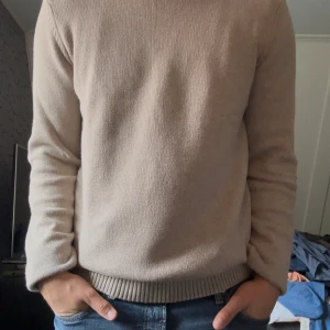 Beige stickad tröja från Dobber - Säljer en stilren beige stickad tröja från Dobber i storlek large. Tröjan är helt slutsåld överallt och kostar 600kr ny. Den är i 100% bomull och är endast provad.  Perfekt för dig som gillar en enkel och clean look med en neutral färg som funkar till det mesta. Modell : dobber lanegan crew neck