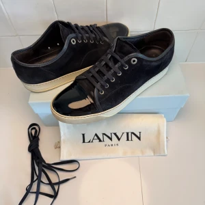 Lanvin skor  - Snygga blå sneakers från Lanvin med ovandel i mocka och en glansig, lackad tå. Skorna har vita sulor och klassisk snörning. Perfekt för dig som gillar stilrena detaljer. Obs inget og tillkommer vid köp!! Bara att höra av sig till oss vid minsta fundering😁