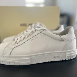 Vita sneakers från Axel Arigato - Hej säljer mina fina Axel Arigatos för ett schysst pris! De är i super bra skick och är endast andvända några fåtal gånger. Dessa kostar 2800 kr i nyttskick. Det är bara att skicka ett meddelande vid frågor!