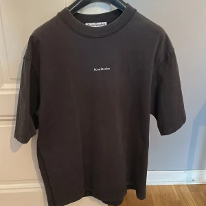 Svart t-shirt från Acne Studios - Oversized svart t-shirt från Acne Studios i 100% bomull. Klassisk passform med korta ärmar och rund halsringning. Diskret Acne Studios-logga tryckt på bröstet. Perfekt för en clean och stilren look.