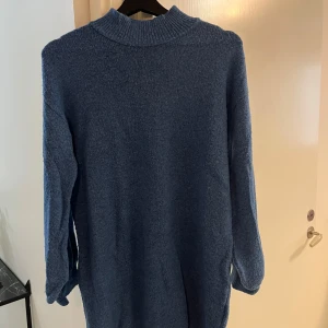 Blå stickad polotröja - Mysig blå stickad polotröja med ribbad krage och muddar vid ärmslut och nederkant. Tröjan har en relaxed passform och är perfekt för kyliga dagar. Enkel och stilren design som funkar till många outfits.