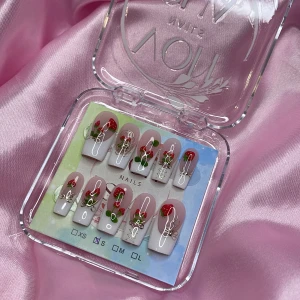 Strawbabe(S);Medium Square - Snygga gelè press on-naglar i storlek S: 15 mm, 11,5 mm, 12 mm, 11 mm, 9 mm , med ljusrosa bas, vita tippar och jordgubbsdekorationer. Naglarna har guldfärgade detaljer och små rosetter för extra effekt. Perfekt för dig som vill ha en söt och unik nagelstil utan att gå till salong.