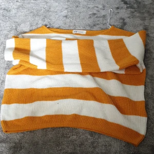 Randig gul och vit stickad tröja H&M - Superfin stickad tröja från H&M med breda gula och vita ränder. Tröjan har en croppad passform, rund halsringning och långa ärmar. Perfekt för dig som gillar färg och vill ha en chill men snygg look.