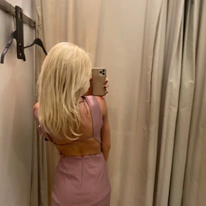 Ljuslila kort klänning med öppen rygg - Säljer en snygg ljuslila kort klänning med öppen rygg och smala band. Klänningen är ärmlös, har en cool rynkdetalj framtill och en tight passform. Perfekt för dig som vill sticka ut med en unik look.