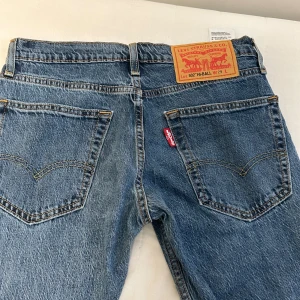 Levi's 502 Hi-Ball blå jeans - Klassiska blå Levi's 502 Hi-Ball jeans med rak passform och femficksdesign. Jeansen har en mellanblå tvätt, tydliga sömmar och ikonisk läderpatch bak i midjan. Tillverkade i slitstarkt bomullsjeansmaterial och har Levis röda etikett på bakfickan.
