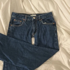 Blå bootcut jeans med raka ben - Snygga blå jeans från gina tricot med klassisk femficksdesign och raka, något utsvängda ben. Jeansen har hög midja och är tillverkade i robust denim med kontrastsömmar. Perfekta för en avslappnad och trendig look. Jeansen har en defekt som ni kan se på bild 4😇 jeansen är ganska små i sin storlek så skulle passa nån med 34 tror jag 