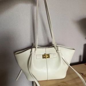 Midi long strap bag - Den virala väskan ifrån Gina Tricot som är helt slutsåld i hemsidan och även i butik. Väskan är i läderimitation med dubbla handtag. Väskan är vit och har guldfärgat spänne. Den har magnetknäppning och innerfack. Dock råkade min kavaj färga av sig på väskan (se bilder) och har försökt få bort och färgen går bort om man kämpar lite. Men självklart kommer jag försöka få bort de flesta till den som köper. Annars är färgen köpt för ett par veckor sedan och har tagit hand om den mycket väl🤍🫶🏾  
