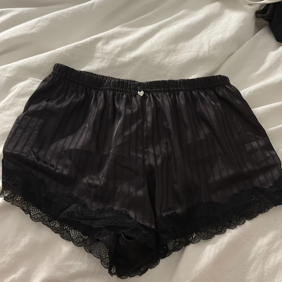 Svarta silkesinspirerade shorts med spets