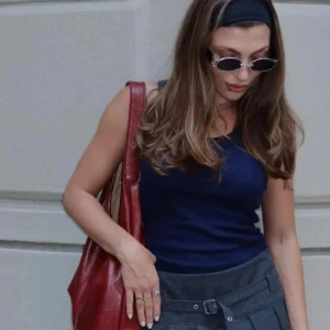 Röd skinnväska + necessär - Jättesnygg röd axelväska i skinn med mjuk, form och bred axelrem. Väskan häkommer med en matchande necessär med dragkedja. Använd endast en gång, nypris 400kr