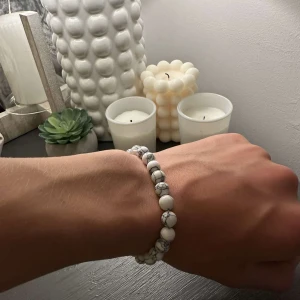 Vitt pärlarmband med marmormönster - Stilrent armband med runda pärlor i vit färg och grått marmormönster. Elastiskt band gör det enkelt att ta på och av. Perfekt accessoar för en clean och modern look.