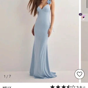 Ljusblå Balklänning  från Nelly - Supersnygg ljusblå långklänning från Nelly med v-ringning och volangdetaljer på axelbanden. Ny pris på klänningen är 1250 men jag säljer för 750kr. Klänningen är använd 1 gång och är tvättad. Tyvärr finns det små fläckar vid botten av klänningen men det är inget som syns när klänningen väl är på. Skriv privat för bild på fläckar. PRIS KAN DISKUTERAS VID SNABBT KÖP