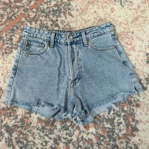 Högmidjade jeansshorts från H&M - Snygga ljusblå jeansshorts från H&M med hög midja. Obs de har ett litet hål (syns på sista bilden)!