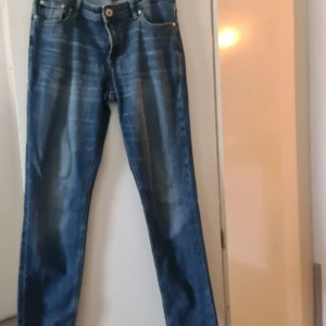 Blå jeansbyxor i rak modell 176/16Y - Snygga blå jeansbyxor i klassisk rak modell med slitningar och kontrastsömmar. Byxorna har fem fickor och stängs med knapp och dragkedja. Perfekta för dig som gillar en tidlös denimlook.